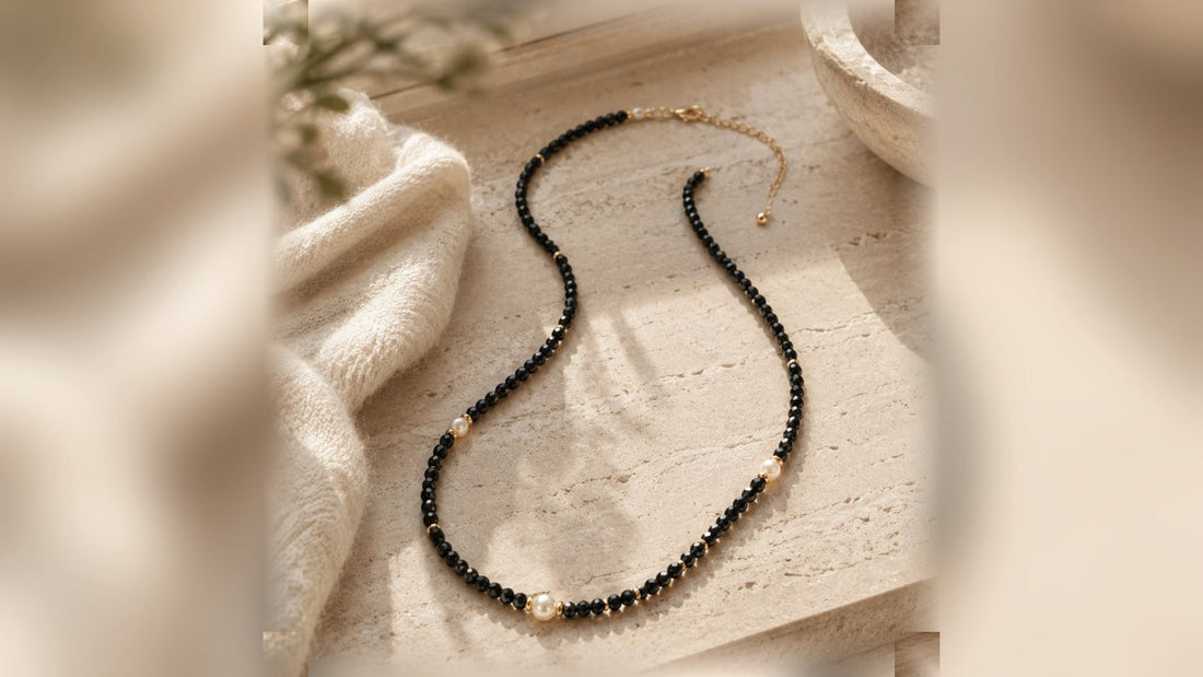 The Nocturne Halo black crescent moon necklace on warm stone and fabric
