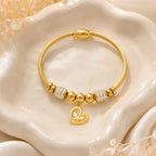 The Amorette Glow gold heart charm bangle for self-love and tender connection, lifestyle styling image