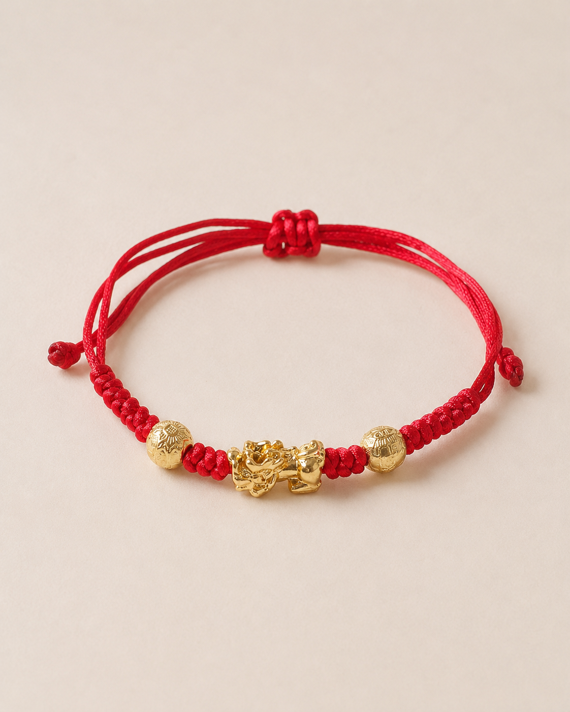 Adjustable red string Pixiu bracelet shown on a warm neutral background