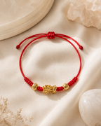 Adjustable Pixiu bracelet with red cord and gold-tone beads on satin