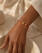Gold-tone Pixiu charm bracelet on an adjustable red cord, worn on the wrist